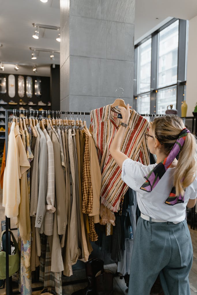 A woman browses clothes on a rack inside a stylish fashion boutique.