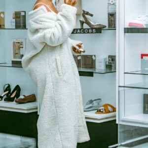 Elegant woman in bathrobe with dyed braided hair shopping in a chic boutique.